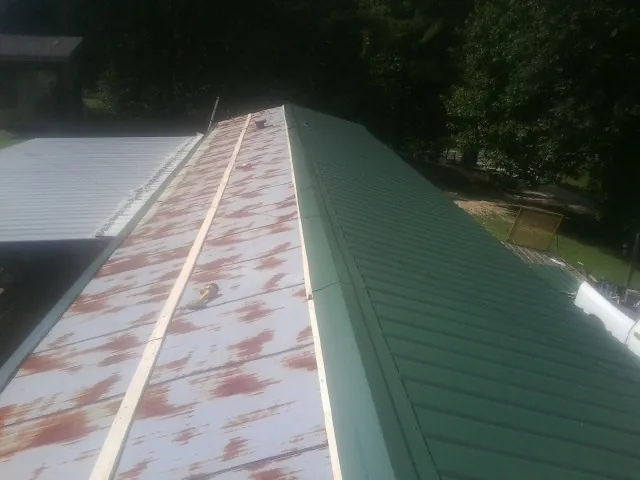 Old rusted panels beside newly installed green metal roofing — Wind Damage Roof Repair by Roofing Brothers in Dade City
