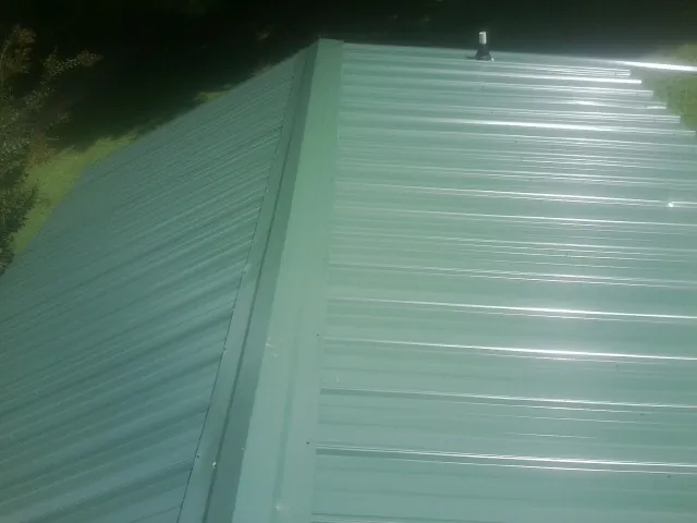New green metal panels meeting at the ridge of a roof — Flat Roof Repair work by our crew in Dade City