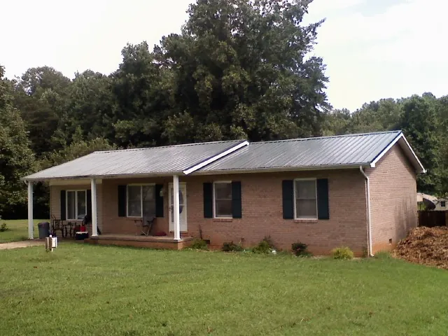 Gray metal roof on a brick ranch house with a side carport in Dade City
