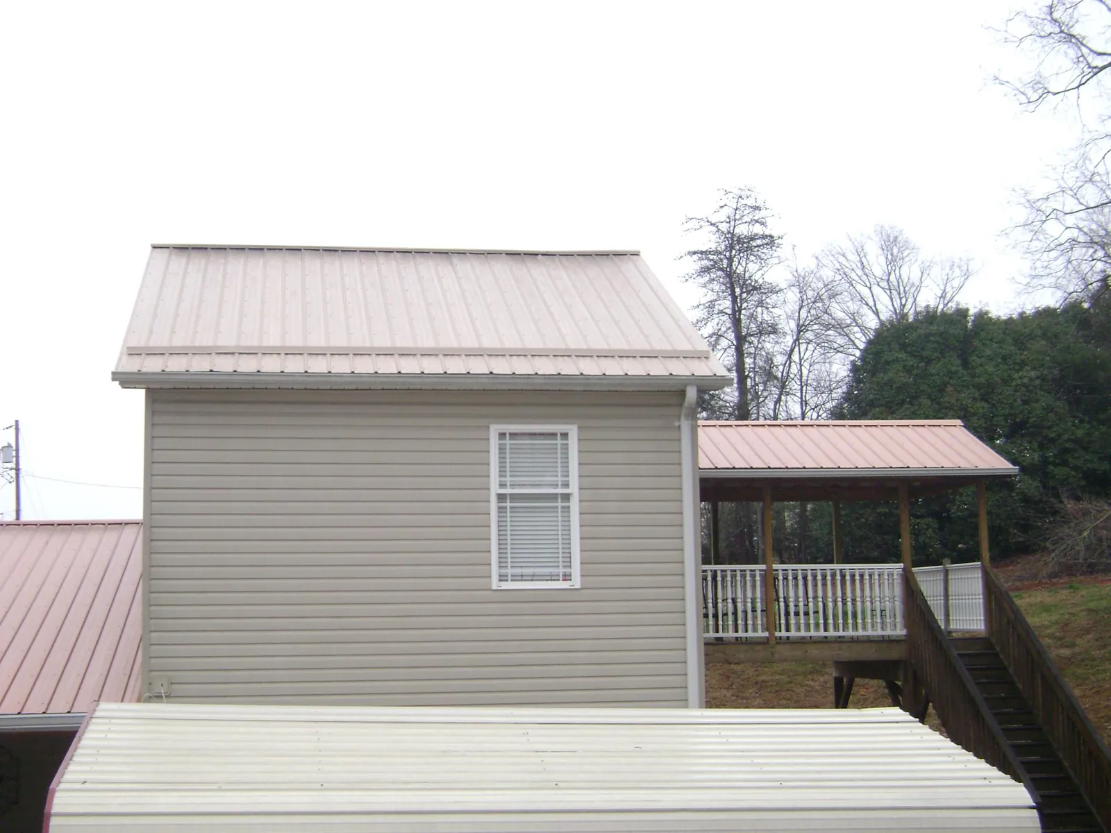 Tan metal roofs on a two story addition and attached porch, from a Roof Replacement job in Dade City