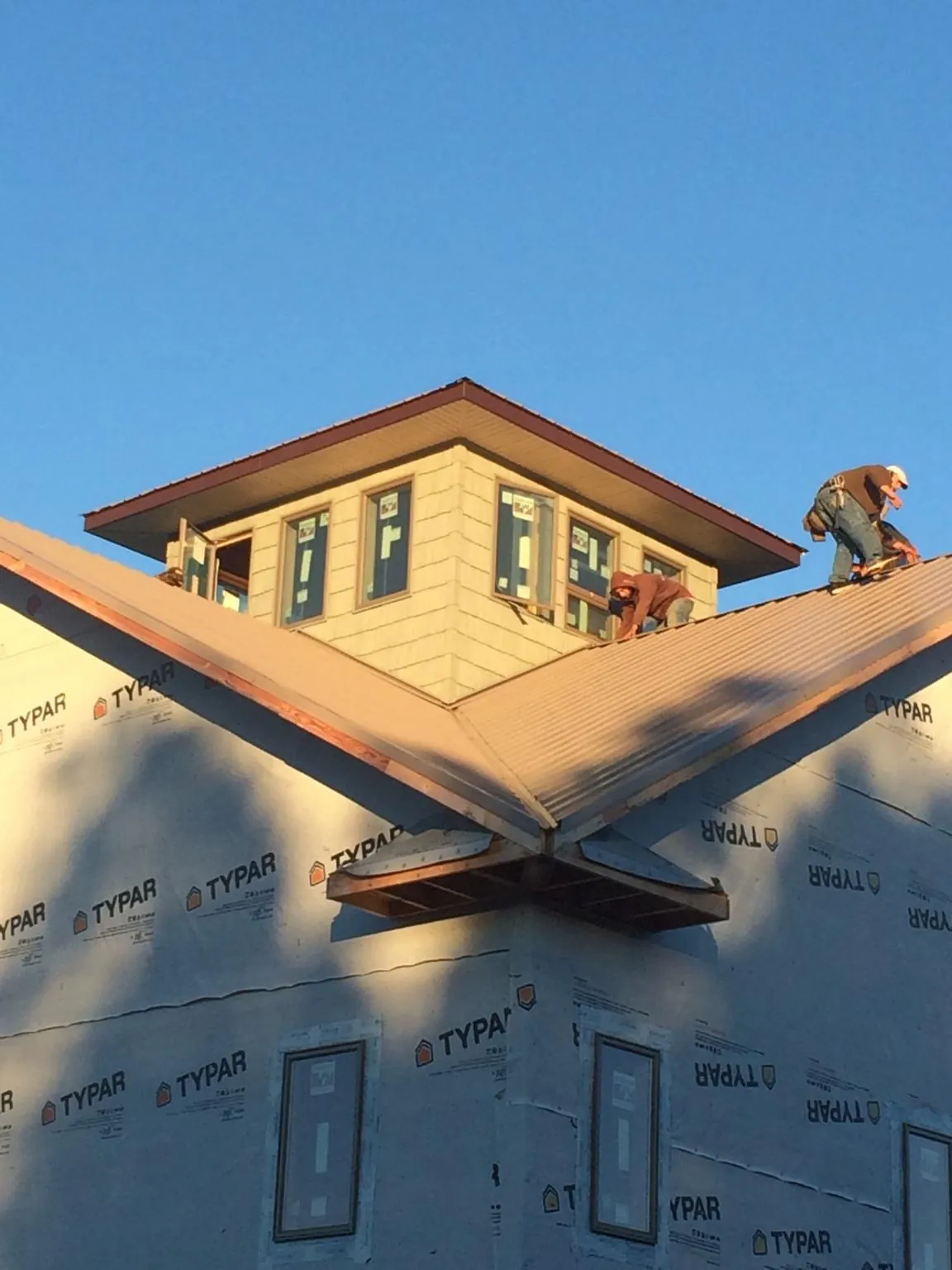 Roofers working around a rooftop cupola on a new metal roof at sunset — Roof Waterproofing in Dade City by Roofing Brothers